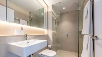 A modern bathroom with a glass shower enclosure, a white sink, and a toilet.