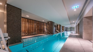 A modern indoor swimming pool with clear lanes, a seating area with chairs, and a well-lit corridor. - Melbourne Private Apartments - Collins Wharf Waterfront, Docklands (Docklands)