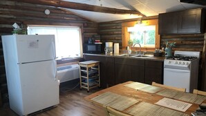 Eine Küchenzeile im Blockhausstil mit Kühlschrank, Herd, Mikrowelle und Spüle.