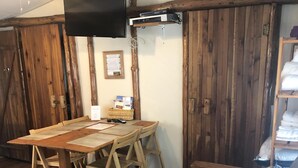 Ein gemütliches Zimmer mit einem Holztisch, einer Couch und einem an einem Holzbalken befestigten Fernseher.