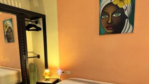 Una habitació d'hotel amb un llit, una nit de nit amb una làmpada, un armari i un quadre a la paret.