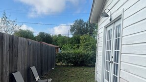 A backyard with a wooden fence, a pathway, and a white building with a door and windows. - King Master Suite Studio (McAllen)