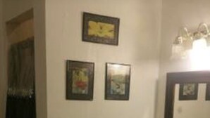 A bathroom with a sink, mirror, and two framed pictures on the wall. - King Master Suite Studio (McAllen)