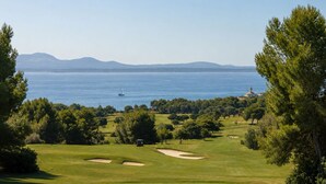 Un parcours de golf avec un phare visible au loin, entouré d’arbres et offrant une vue dégagée sur la mer.