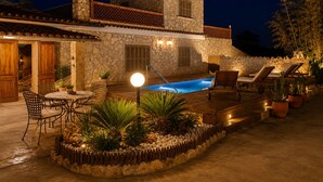 Une villa en pierre dotée d’une piscine, d’un espace extérieur aménagé et d’un patio bien éclairé.