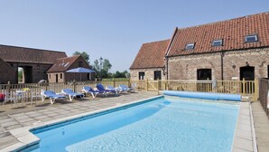 Une piscine avec des chaises longues et une terrasse en bois.