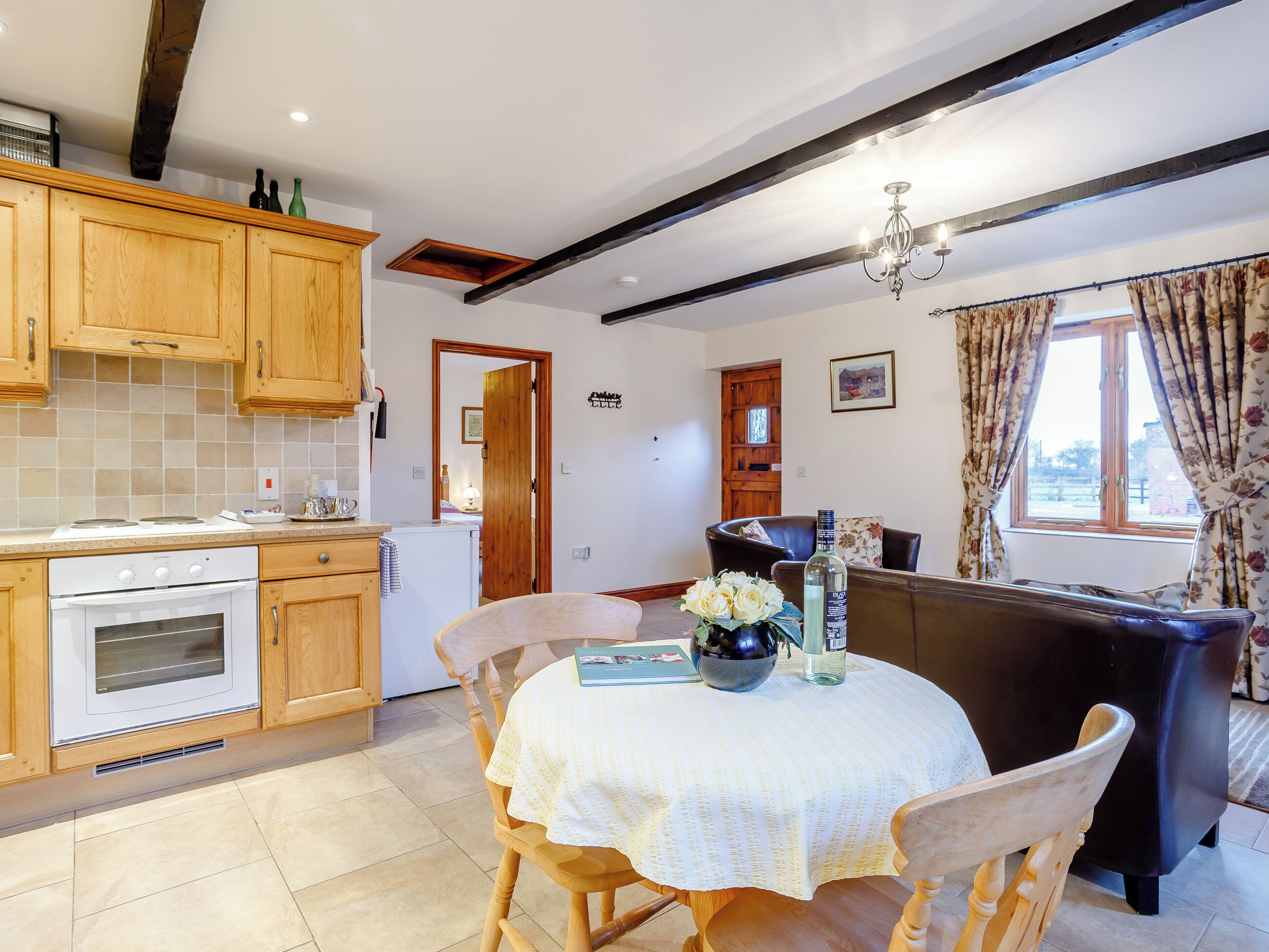 A kitchen with wooden cabinets, a white stove, and a dining area with a table and chairs.