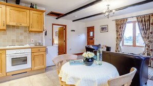 Une cuisine avec des meubles de rangement en bois, une cuisinière blanche et un coin repas comprenant une table et des chaises.