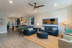 Un salon moderne avec un canapé bleu, une table basse et un ventilateur de plafond.