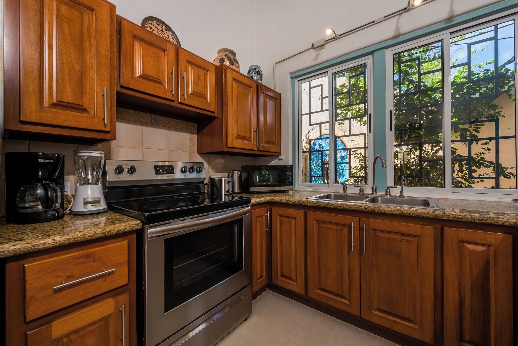 A kitchen with wooden cabinets, a granite countertop, a stove, a microwave, and a sink.