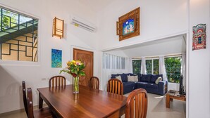 A dining area with a wooden table and chairs, a vase with flowers, and a blue painting on the wall.