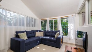 A living room with a dark blue sectional sofa, a flat-screen TV, and a wooden coffee table.