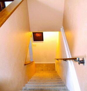 A staircase with a handrail on the right, a wall-mounted light fixture, and a door at the top.
