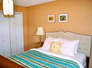 Een hotelkamer met een bed, een nachtkastje, een lamp en twee foto's in lijsten aan de muur.