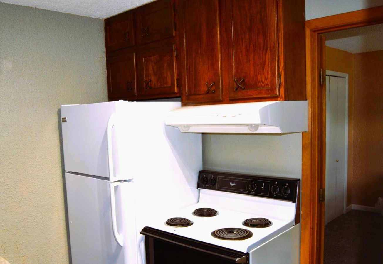 Une cuisine avec un réfrigérateur blanc, une cuisinière et des armoires en bois.