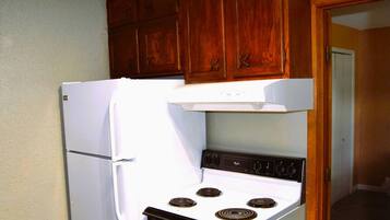 Une cuisine avec un réfrigérateur blanc, une cuisinière et des armoires en bois.
