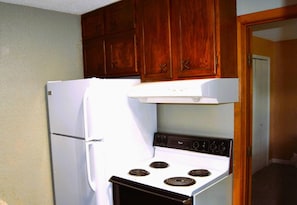 A kitchen with a white refrigerator, a stove, and wooden cabinets.