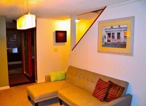 A living room with a sofa, a small table, and a staircase.