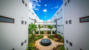 Un edificio moderno con un patio central, varios balcones y un cielo despejado.