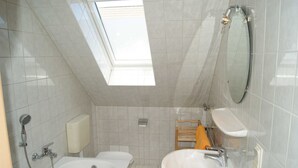 Een moderne badkamer met dakraam, ligbad, wastafel en douche.