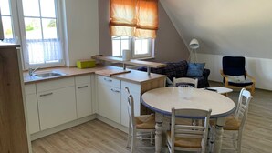 Een praktische keuken met een spoelbak, houten aanrecht en een eethoek met een ronde tafel en stoelen.
