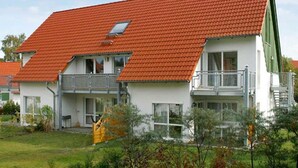 A two-story building with a red-tiled roof, balconies, and a green awning. - Apartment on the beach - apartment (Karlshagen)