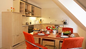 A modern kitchen with a dining area. It includes a kitchen island, a dining table with chairs, and a kitchen counter with appliances. - Apartment on the beach - apartment (Karlshagen)