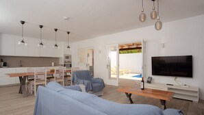 En moderne stue med sofa, spisebord og fjernsyn.