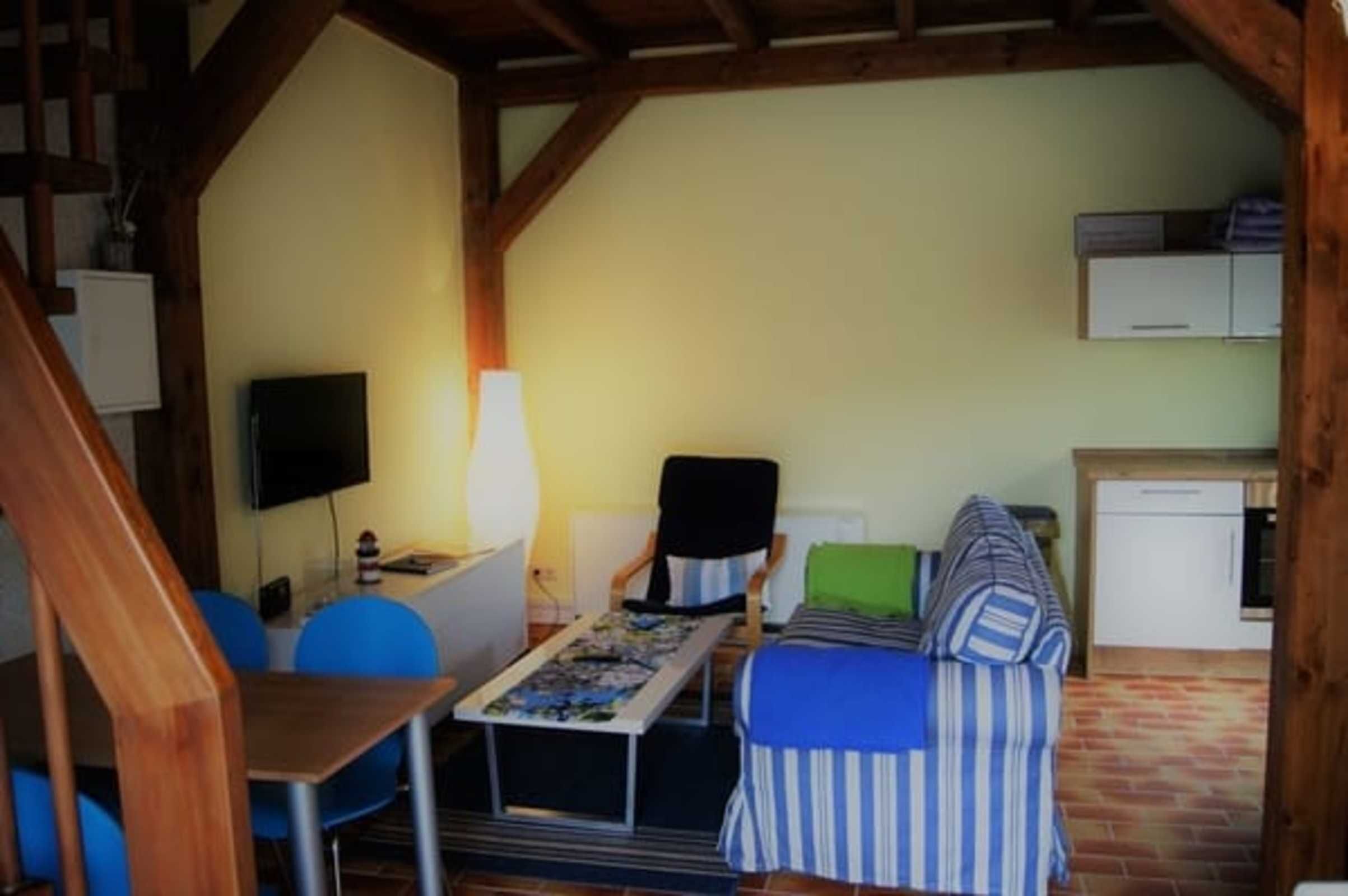 A cozy room with a bed, a desk, a chair, and a TV.