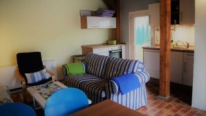En hyggelig stue med en stribet sofa, et træbord og et køkken med skabe og vask.