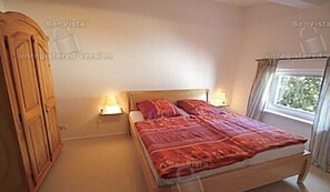 Quarto com cama de madeira, duas luminárias de cabeceira, guarda-roupa e janela com cortinas.