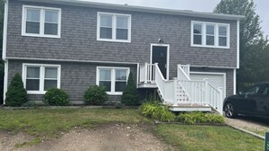 A two-story residential building with a front deck and a garage. -  Great 5 Bedroom in Beautiful Bonnet Shores, Narragansett R (Narragansett)