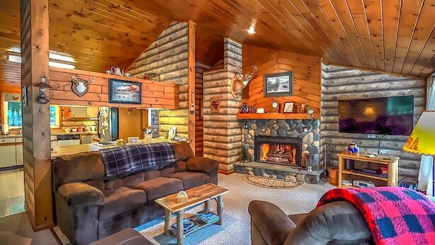 Ein gemütliches Blockhaus-Interieur mit Kamin, Fernseher und Essbereich.