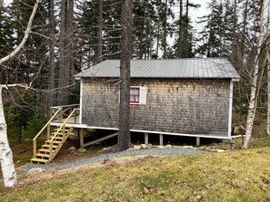 A small wooden cabin with a metal roof, surrounded by trees. - Luxurious & secluded mansion and separate cabin with stunning ocean views! (Winter Harbor)