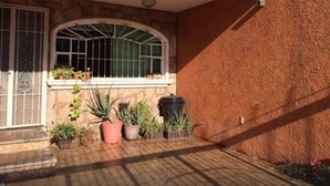 A covered patio area with a stone wall, a window with metal bars, and potted plants. - 4 Recamaras Zona Sur WiFi Jardin Cochera (Zapopan)