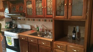A kitchen with wooden cabinets, a stove, a sink, and a wine bottle. - 4 Recamaras Zona Sur WiFi Jardin Cochera (Zapopan)