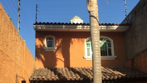 A two-story house with a tiled roof, a small balcony, and a palm tree in the foreground. - 4 Recamaras Zona Sur WiFi Jardin Cochera (Zapopan)