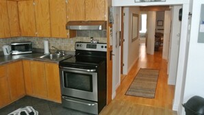 A kitchen with wooden cabinets, a stainless steel stove, and a microwave. - The Mont-Royal - appattement apartment (montreal)