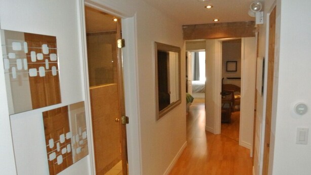 A hallway with wooden flooring, white walls, and a door leading to another room. - The Mont-Royal - appattement apartment (montreal)
