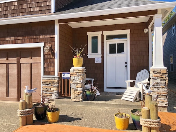 A house with a front porch, stone pillars, a white door, and two Adirondack chairs.