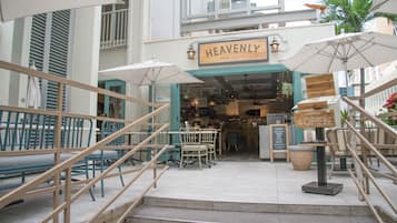 An outdoor seating area with wooden chairs and tables, a staircase, and a sign that reads "HEAVENLY ISLAND LIFESTYLE".