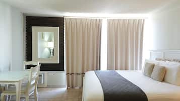 A hotel room with a bed, a desk, a chair, and a mirror.