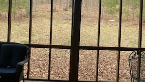 A covered porch with a view of a wooded area.