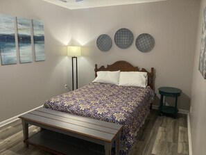 Een slaapkamer met een bed, nachtkastje, vloerlamp en drie decoratieve items aan de muur.