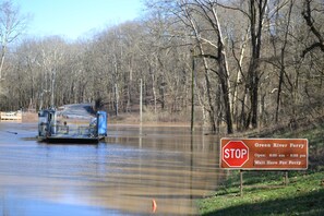 Een veerboot steekt een rivier over, met een stopbord dat de Green River Ferry dienst aangeeft.