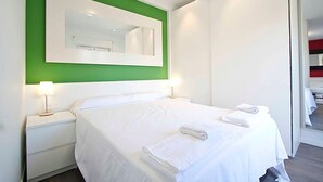 Ett hotellrum med en stor säng, två sängbord, en grön accentvägg och en spegel ovanför sängen.