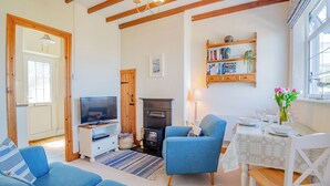 A living room with a television, blue sofas, a fireplace, and a bookshelf.