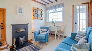 A cozy living room with a fireplace, a dining table set for two, and a blue sofa.
