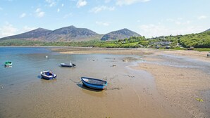 A beach with boats, a mountain, and a small settlement.