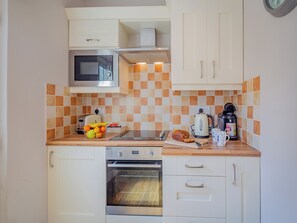 Una cocina con microondas, horno y salpicadero de azulejos.